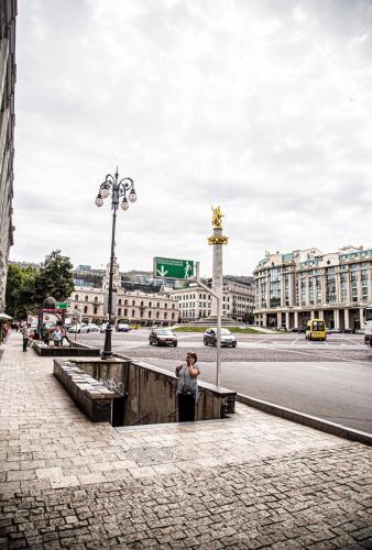 a woman standing on a sidewalk in front of a street at my house in Tbilisi City