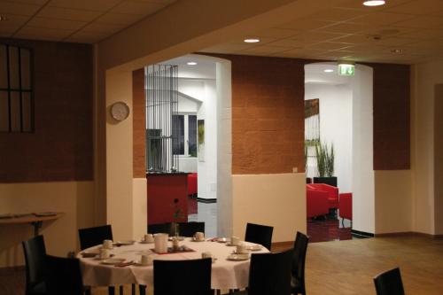 a dining room with tables and chairs and a clock at ALCATRAZ Hotel am Japanischen Garten in Kaiserslautern