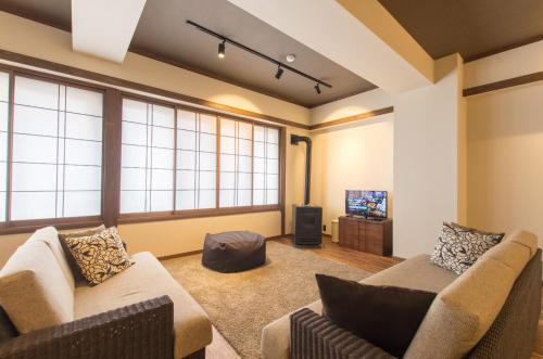 a living room with two couches and a tv at Tanuki Nozawa in Nozawa Onsen