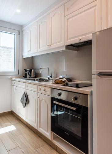 a kitchen with white cabinets and a black oven at White Rock Milos Suites in Adamas