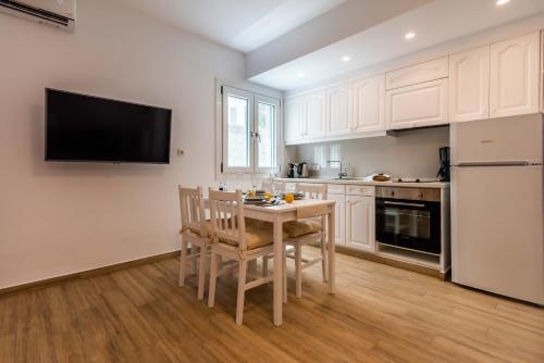 a kitchen with white cabinets and a table and chairs at White Rock Milos Suites in Adamas