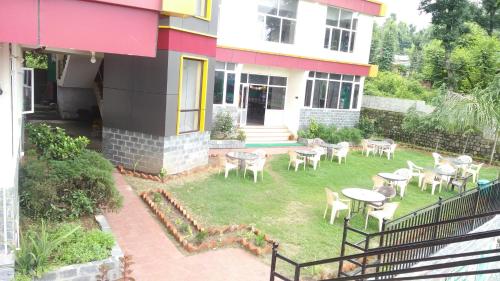 a yard with tables and chairs in front of a house at Highland Village Resort in Dharmsala