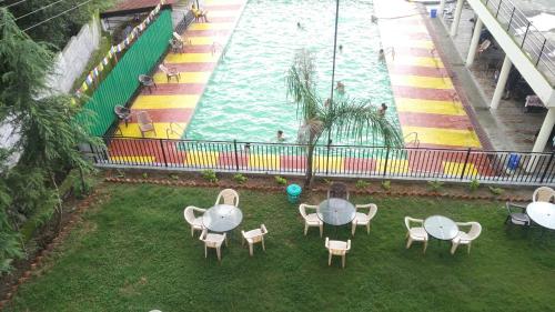 a pool with tables and chairs next to a water slide at Highland Village Resort in Dharmsala