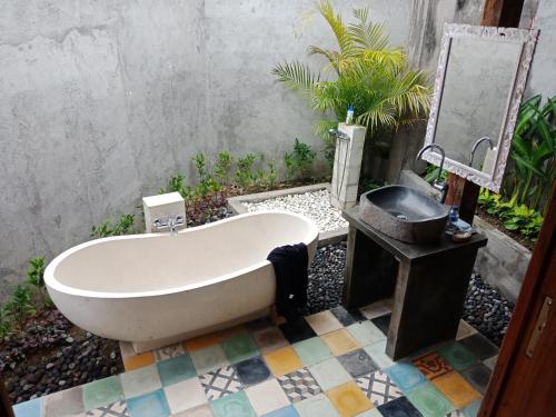 a bath tub sitting on a tiled floor with a sink at Ubud Sawah Scenery Villa and Homestay in Tegalalang