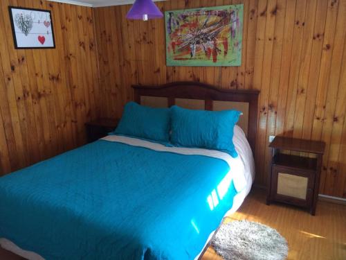 1 dormitorio con 1 cama con sábanas azules y paredes de madera en Casa en Santiago equipada, en Santiago