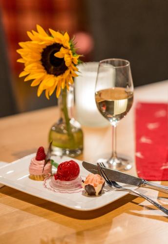 a table with a plate of food and a glass of wine at Hotel Erlebniswelt Stocker in Schladming