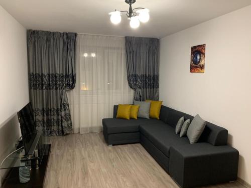 uma sala de estar com um sofá preto e almofadas amarelas em Apartament Cristina em Bucareste