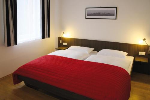 a bedroom with two beds with a red blanket at ALCATRAZ Hotel am Japanischen Garten in Kaiserslautern