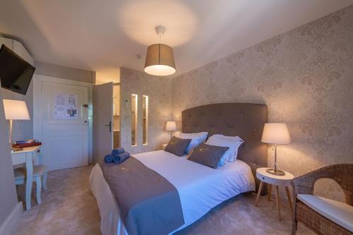 a bedroom with a large bed and a table at Hôtel Au Coq Dort Spa in Châtillon-sur-Chalaronne