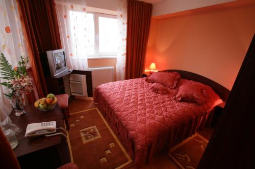 a bedroom with a bed and a desk and a phone at Hotel Grim in Craiova