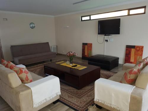 a living room with two couches and a tv at One Oban Place in Pinetown