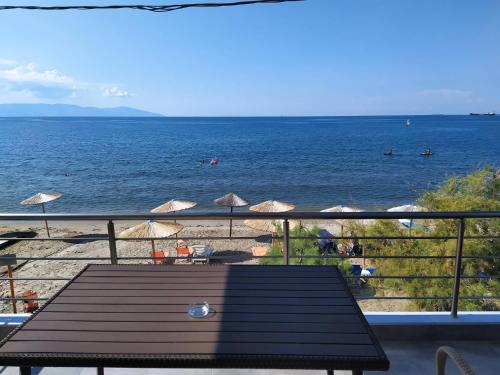 a view of a beach with a table and umbrellas at Bebas Apartments Nea Karvali in Néa Karváli