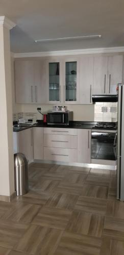 a kitchen with white cabinets and a wooden floor at One Oban Place in Pinetown