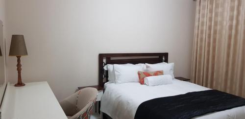 een slaapkamer met een bed met witte lakens en kussens bij One Oban Place in Pinetown