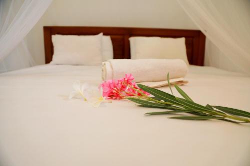 a white bed with a bouquet of flowers on it at Nisala Guest in Galle