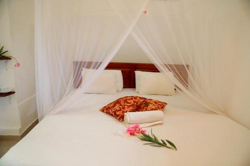 Una cama blanca con dosel con flores. en Nisala Guest, en Galle