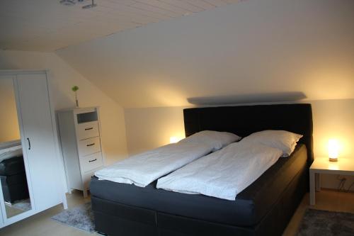a bed in a bedroom with two lights on at Ferienwohnung Abersfelder mit Balkon in Wildflecken