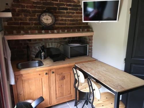 La cuisine est équipée d'une table, d'un évier et d'un four micro-ondes. dans l'établissement La maison du bonheur 