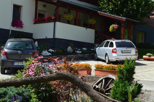 two cars parked in front of a house with flowers at Apartment Lazoň in Pavčina Lehota
