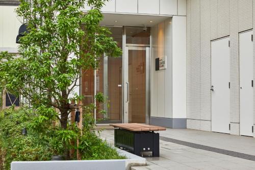 a bench in front of a building with a tree at Hotel Lumiere Grande Nagareyama-Otakanomori in Nagareyama