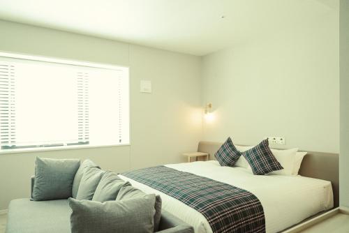 a white bedroom with a bed and a couch at Hotel It Osaka Shinmachi in Osaka