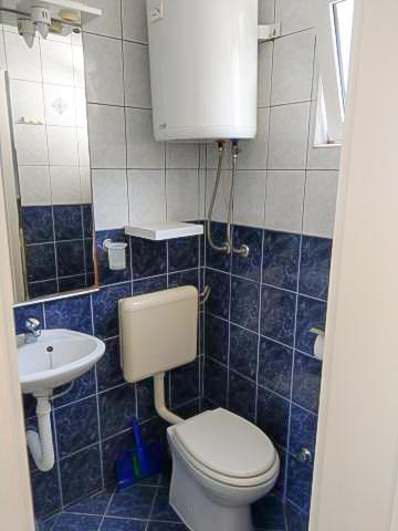 a blue tiled bathroom with a toilet and a sink at Luka 3 in Podgora