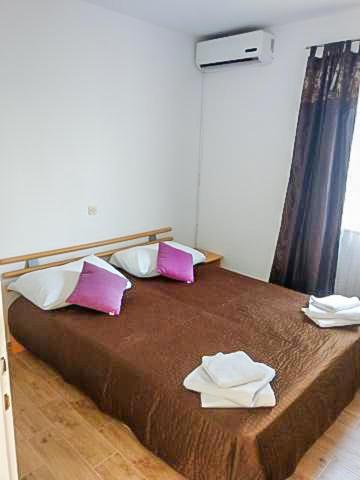 a bedroom with a bed with pink and white pillows at Luka 3 in Podgora