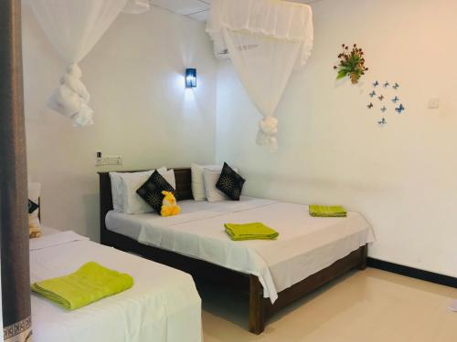 two beds in a room with white walls at Sigiri Saman Home Stay in Sigiriya