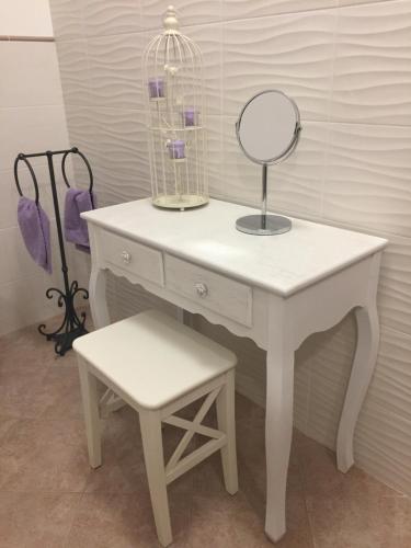 a white dressing table with a mirror and a stool at A Casa di Laura in Occhiobello