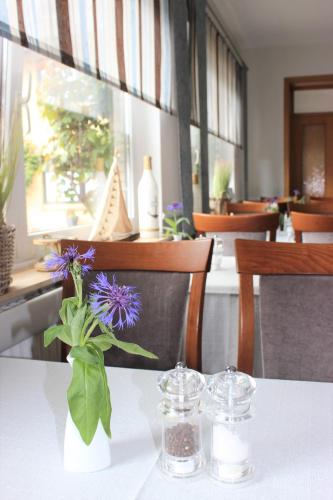 a table with a vase with purple flowers on it at Hotel Gasthuus Spieskamer in Hasselberg