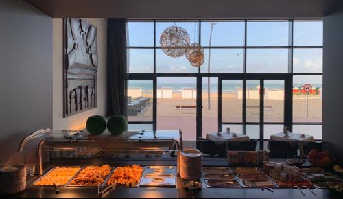 a kitchen with a counter with food and a large window at Hotel Villa Select in De Panne