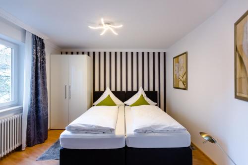 - une chambre avec un lit doté d'oreillers blancs et verts dans l'établissement City Apartment an der Caracalla Therme, à Baden-Baden