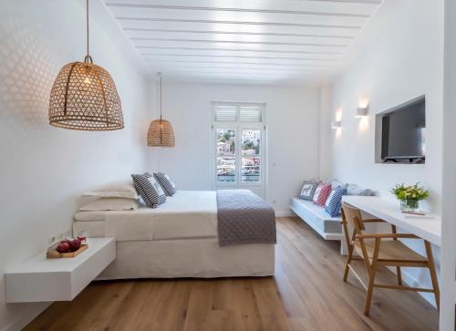a white bedroom with a bed and a table at Upper Hydra in Hydra