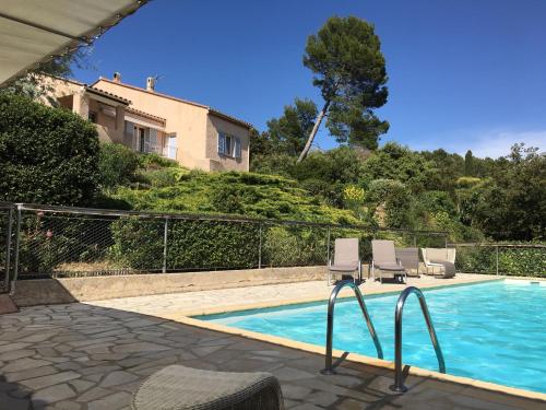 een zwembad met twee stoelen en een huis bij Leis Arbouso in Lorgues