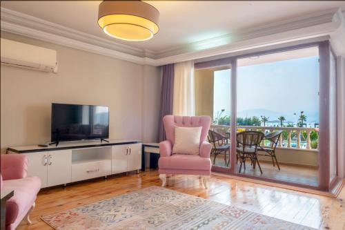 a living room with a tv and a chair and a balcony at Fethiye City Aparts in Fethiye