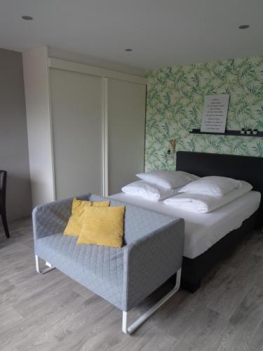 een slaapkamer met een bed en een bank met een geel kussen bij Sfeervolle 2 persoons studio in Bakkeveen in Bakkeveen