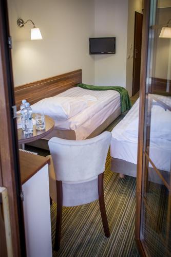 a hotel room with two beds and a table and chair at Leśne Patio in Katowice