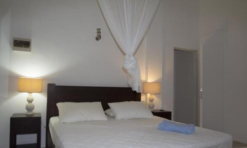 a bedroom with a bed with white sheets and two lamps at La Batie selfcatering Apartment in Beau Vallon