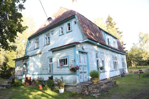an old blue house with flowers in front of it at Annenhof Holiday House in Pudisoo