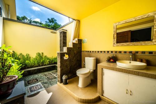 a bathroom with a toilet and a sink and a window at Kelapa Cottage in Amed
