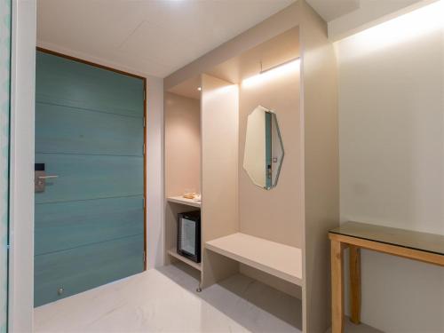 a walk in closet with a blue door and a mirror at โรงแรมโกลว์ รัตนา เพลส in Songkhla