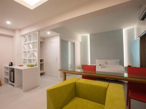 a living room with a yellow couch and a bed at โรงแรมโกลว์ รัตนา เพลส in Songkhla