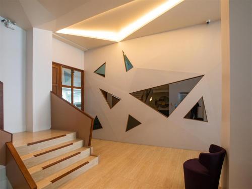 a staircase in a house with a geometric wall at โรงแรมโกลว์ รัตนา เพลส in Songkhla