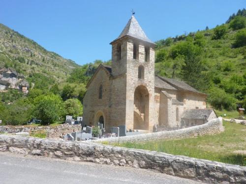 an old stone church next to a road at La maison d'Arnal in Sainte-Énimie