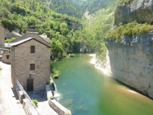 a river with a building next to a mountain at La maison d'Arnal in Sainte-Énimie