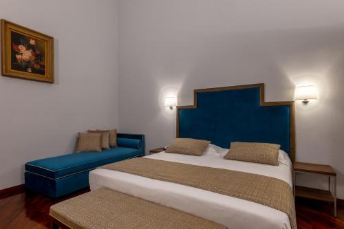 a bedroom with a large bed and a blue headboard at Bosone Palace in Gubbio