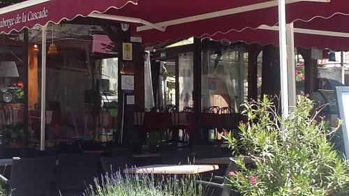 a patio with a table and chairs and an umbrella at LA PETITE MAISON D'ARNAL in Sainte-Énimie