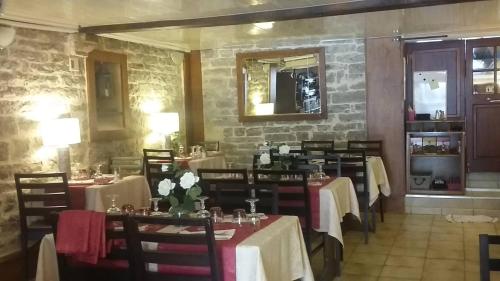 a restaurant with tables and chairs and a stone wall at LA PETITE MAISON D'ARNAL in Sainte-Énimie