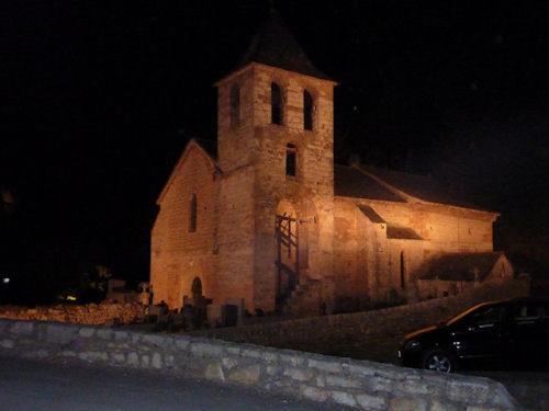 a large brick church at night with a car parked in front at LA PETITE MAISON D'ARNAL in Sainte-Énimie