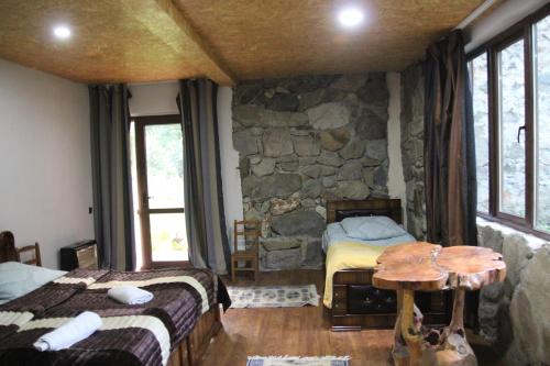 a bedroom with two beds and a stone wall at Dali Kaldanis Guest House in Becho in Mestia